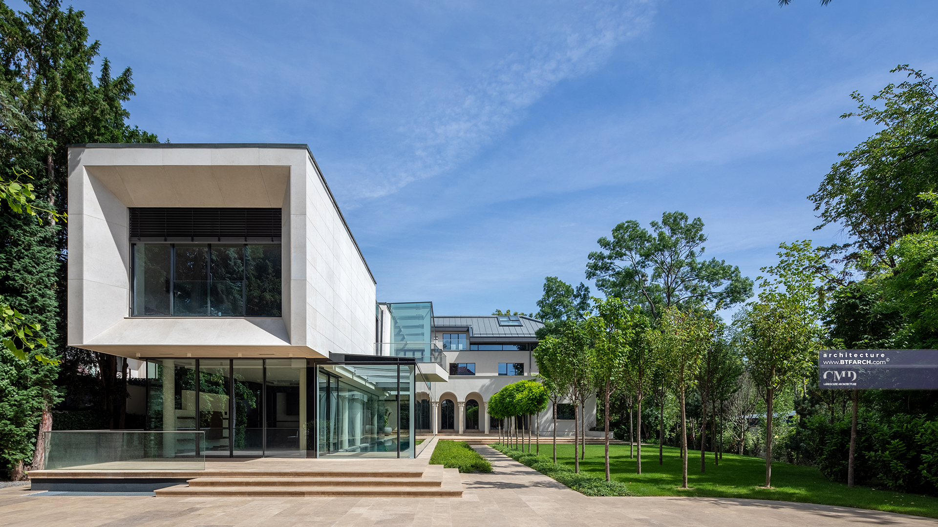 Contemporary glass and stone extension overlooking a classically aligned garden with trimmed trees